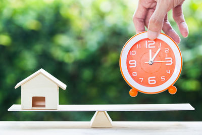 Close-up of hand holding clock against building