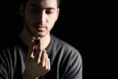 Portrait of young man making face against black background