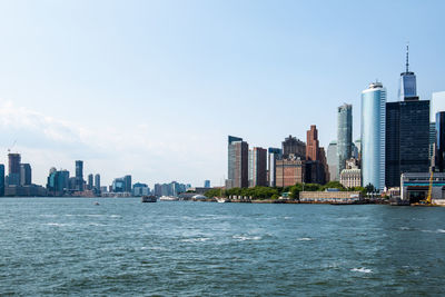 Sea by buildings against sky in city