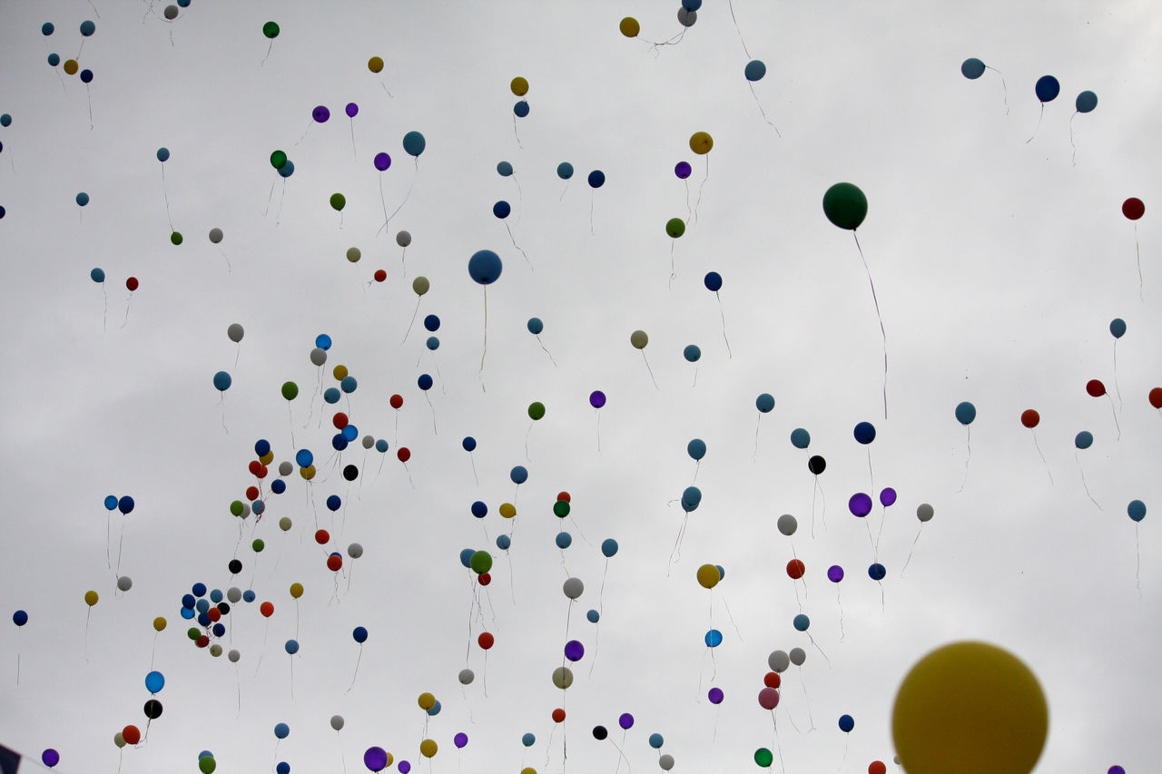 LOW ANGLE VIEW OF MULTI COLORED BALLOONS FLYING IN MID-AIR