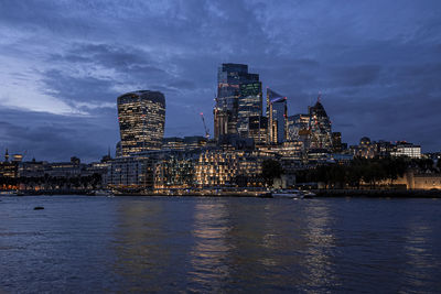 View of illuminated modern financial district skyscrapers from river thames