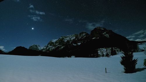 Scenic view of snow covered mountains against sky at night