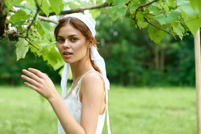 Portrait of smiling young woman standing against plants