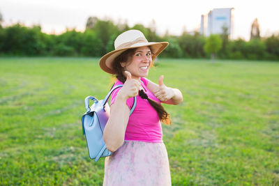 Portrait of woman wearing hat standing on grass