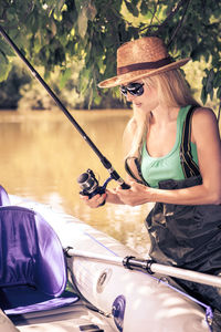 Mid adult woman wearing sunglasses fishing while canoeing on lake