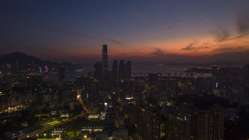 Illuminated cityscape against sky during sunset