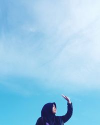 Low angle portrait of man standing against blue sky