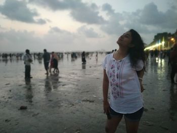 Friends standing on beach against sky