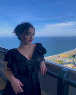 Portrait of young woman looking at sea against sky