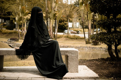 Midsection of woman with cross on tree