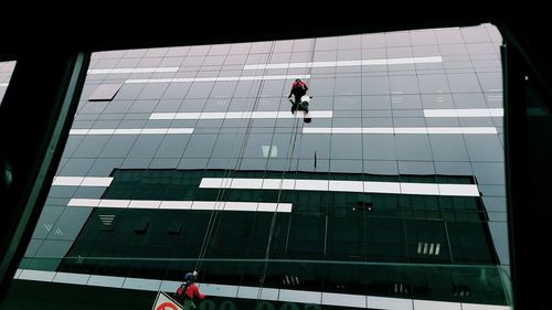 Low angle view of people working on glass building