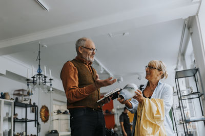 Male entrepreneur talking with senior woman buying vase from antique store
