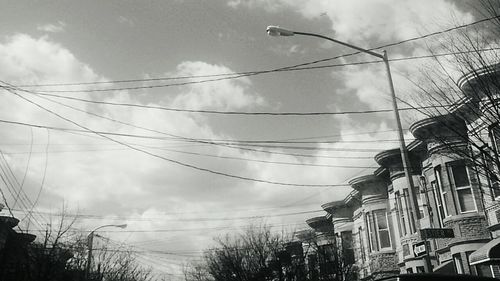 Low angle view of power lines against cloudy sky