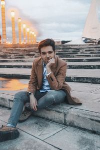 Portrait of young man sitting on staircase in city