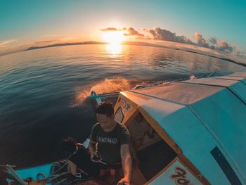 High angle view of man on sea against sky during sunset