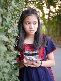 Portrait of young woman standing against plants