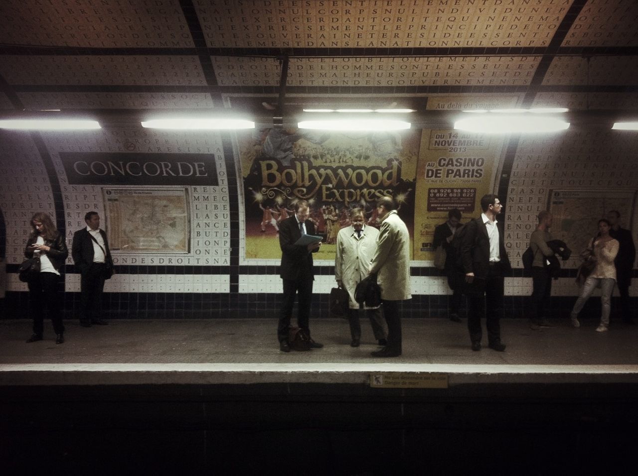 men, indoors, text, railroad station, person, lifestyles, illuminated, subway station, western script, subway, walking, public transportation, large group of people, communication, railroad station platform, non-western script, transportation, travel, full length