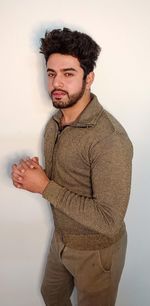 Portrait of young man standing against white background