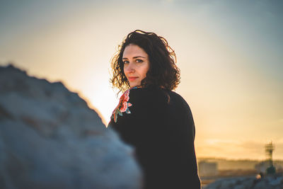 Portrait of young woman standing at beach during sunset