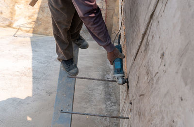 Close up a hand of worker uses a grindstone to cut steel that has emerged from a concrete wall