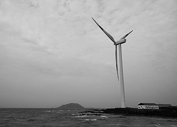 Wind turbines in sea against sky