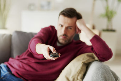 Portrait of young man sitting on sofa at home
