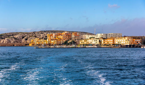 Scenic view of sea and buildings against blue sky