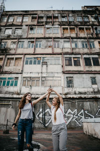 Smiling friends standing against building in city