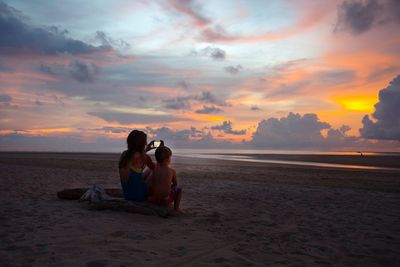 Woman on beach against sky during sunset