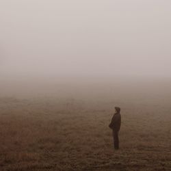 Man standing on field amidst fog