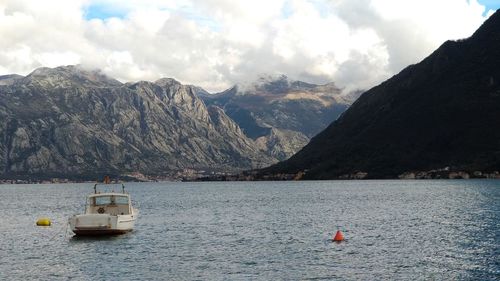 Sailboat sailing on sea by mountains against sky