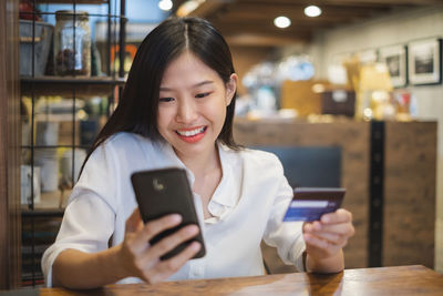 Smiling young woman using mobile phone at home