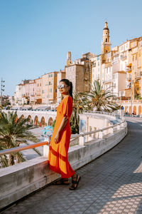 Young woman against buildings in city against sky