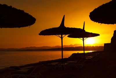 Amazing beautiful red sunset on the sea coast. dark silhouettes of beach umbrellas