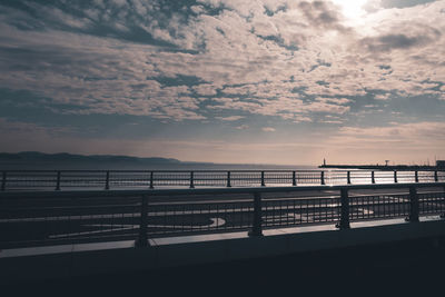 Silhouette bridge over sea against sky during sunset