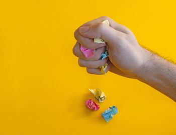 Cropped hand of woman holding dental equipment against yellow background