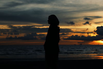 Silhouette man standing on beach against sky during sunset