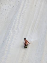 High angle view of boy sitting on snow