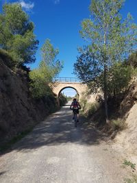 Man riding bicycle on road against sky