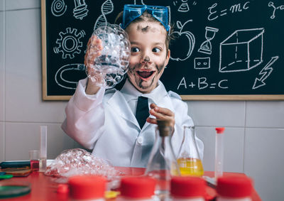 Boy wearing lap coat while standing in classroom
