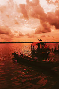 Silhouette boat sailing on sea against sky during sunset