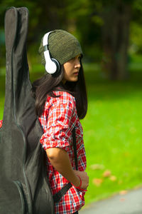 Side view of woman carrying guitar at park