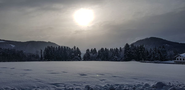 Snow covered landscape against sky during winter