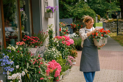 Portrait of woman standing by flowers