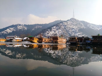 Buildings by lake against sky during winter