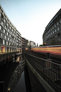 Light trails on city buildings against clear sky