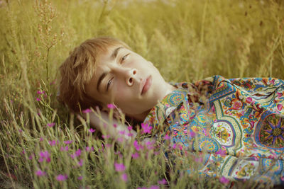 Portrait of young man lying on grassy land