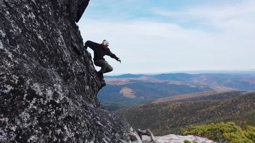 Man standing on rock against sky