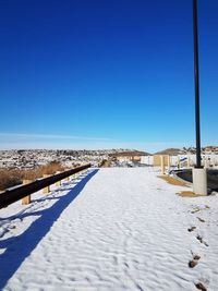 Snow covered beach against clear blue sky