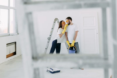 Happy smiling married couple engaged in renovation repair in the room of the house preparing to move